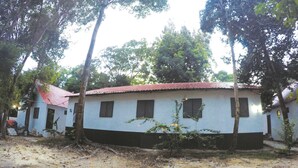 A two-story building with a red roof, surrounded by trees and a dirt ground. - Perhentian Tivoli Inn (Pulau Perhentian Kecil)