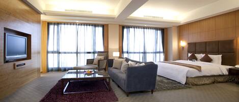 Una habitación de hotel con una cama grande, un sofá, una mesa de centro y un televisor.