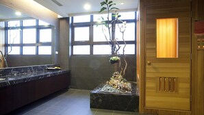 A modern bathroom with a marble sink, a wooden door, and a window with blinds. - Justwin Grand Hotel (Tainan)