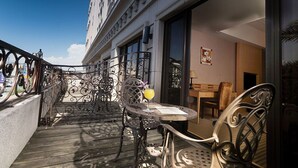 A balcony with wrought iron railings, a table with a chair, and a window overlooking the street. - Justwin Grand Hotel (Tainan)