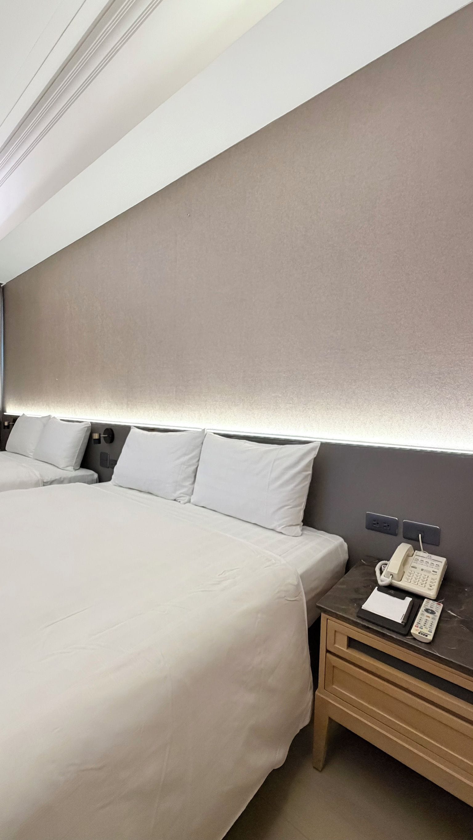 A hotel room with a large bed, bedside tables, a telephone, and a wall-mounted light.