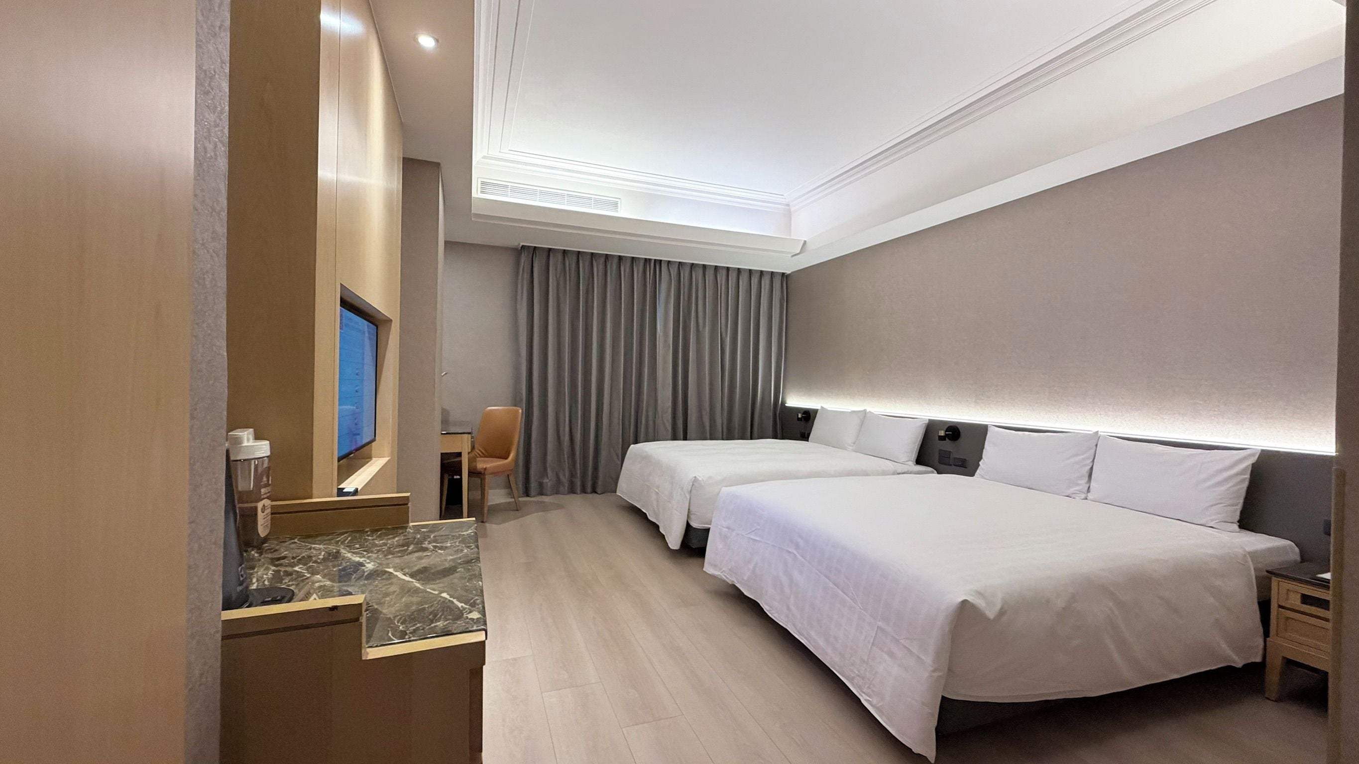 Una habitación de hotel con dos camas, televisión, escritorio y una silla.
