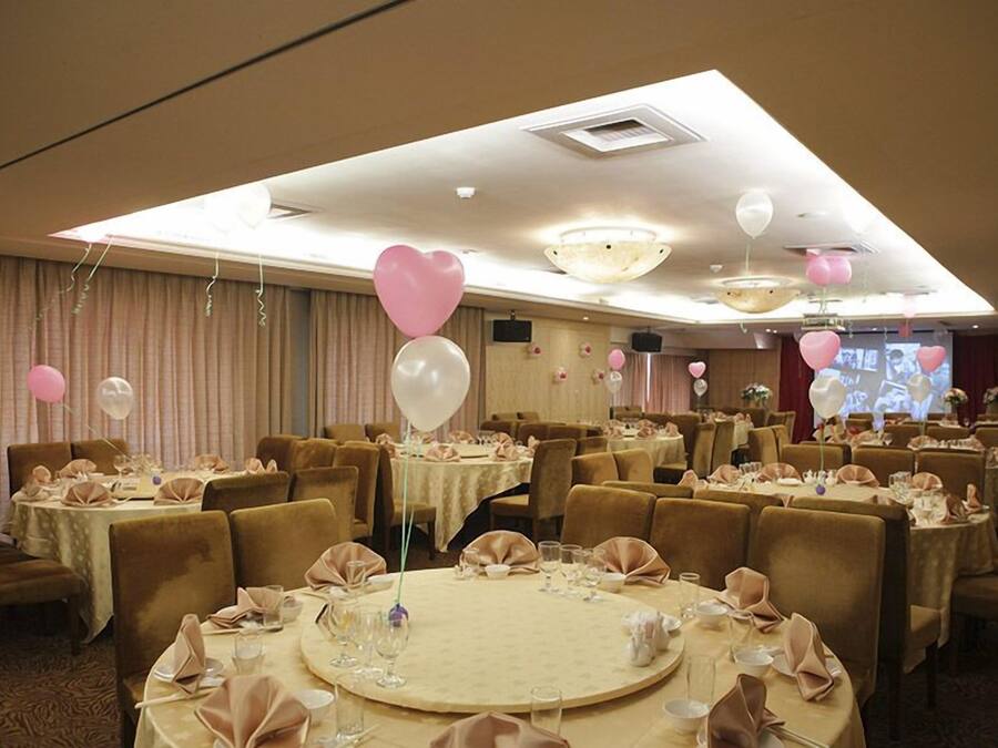 A banquet hall with round tables set for dining, featuring a warm color scheme and elegant decor.