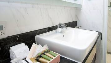 A bathroom with a white sink, black countertop, and marble backsplash. There is a box of toiletries on the countertop.