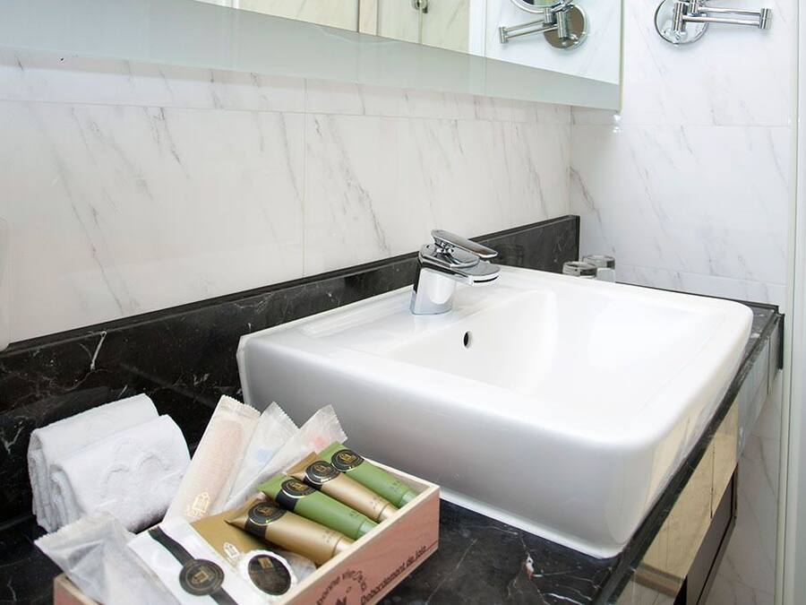 A bathroom with a white sink, black countertop, and marble backsplash. There is a box of toiletries on the countertop.
