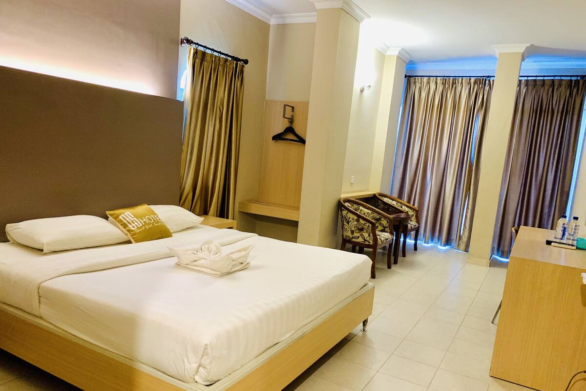 Une chambre d’hôtel avec un grand lit, un bureau et une chaise.