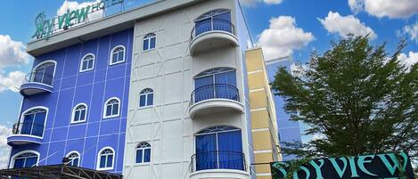 A hotel building with a blue facade, multiple balconies, and a sign reading "Skyview Hotel".