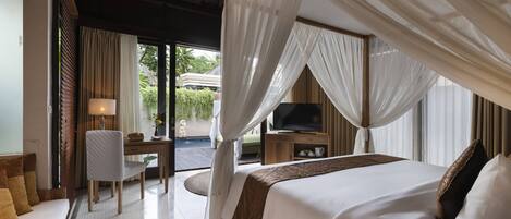 A bedroom with a canopy bed, a desk with a chair, a television, and a view of the outdoors.