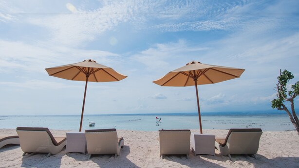 A beach view with lounge chairs and umbrellas.