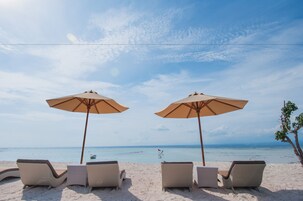 Vista da praia com espreguiçadeiras e guarda-sóis.