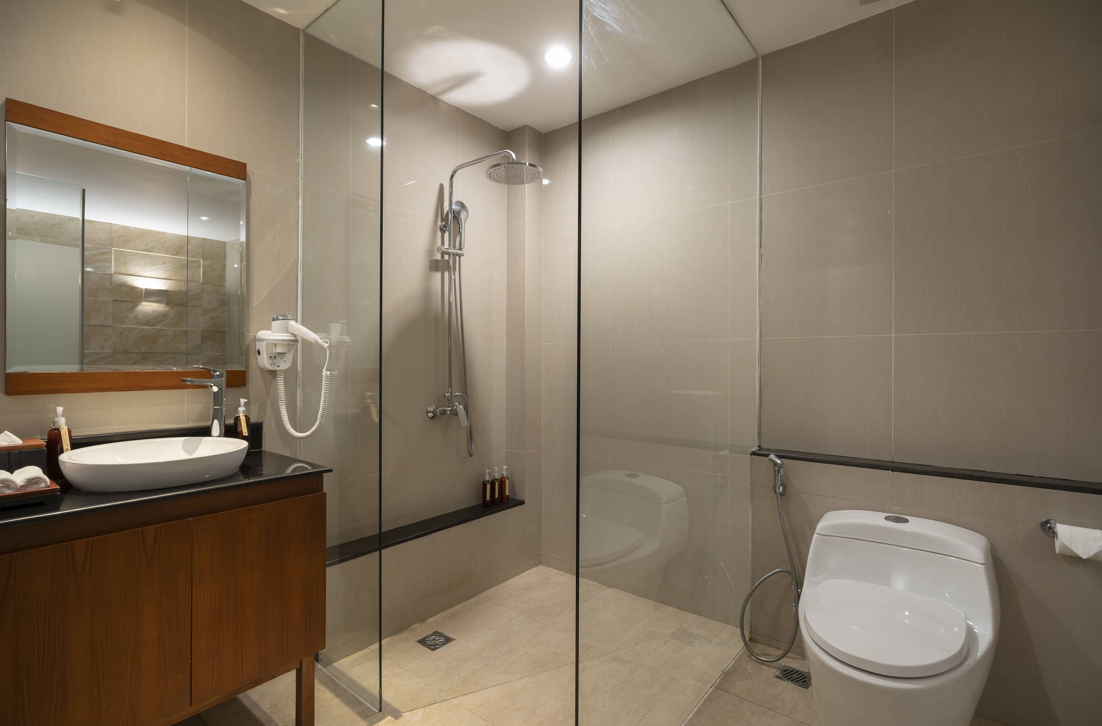 A modern bathroom with a glass-enclosed shower, a white sink, and a toilet.
