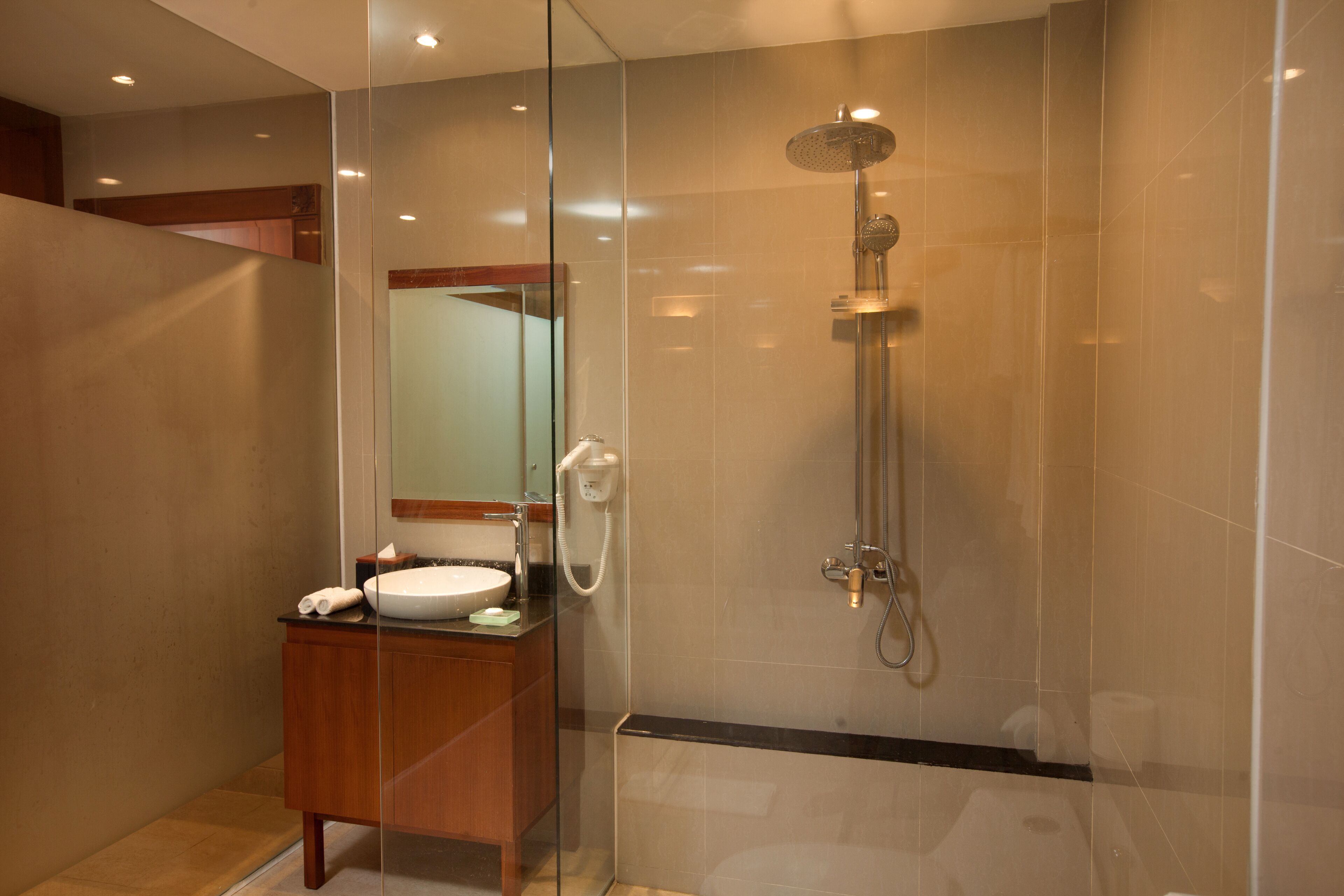 A modern bathroom with a glass-enclosed shower, a wooden vanity, and a large mirror.