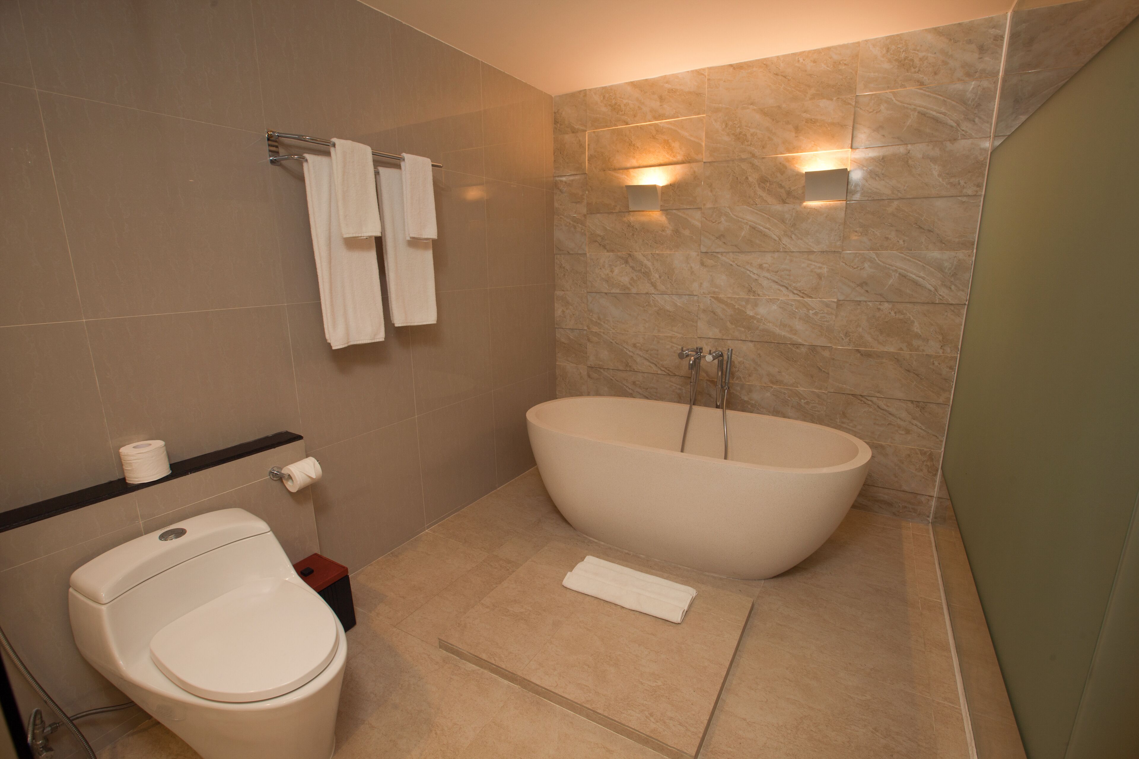Un baño moderno con una bañera independiente, un inodoro y un perchero para toallas.