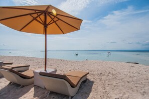 A beach with lounge chairs and an umbrella. - d’Nusa Beach Club and Resort (Lembongan Island)
