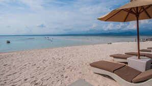 A beach with lounge chairs and an umbrella. - d’Nusa Beach Club and Resort (Lembongan Island)