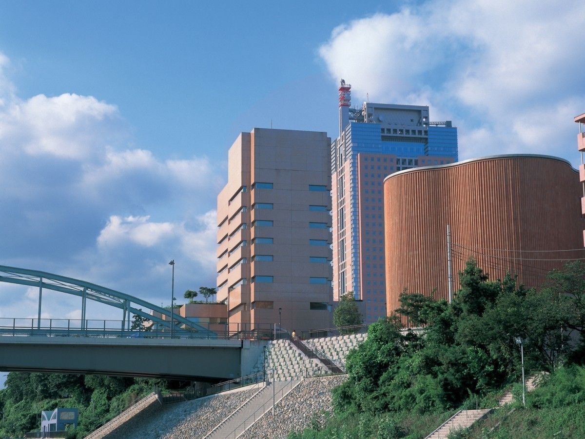 Un edificio de varios pisos con un diseño moderno, un puente y una escalera que lleva al edificio.