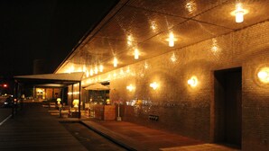 A brick building with a covered outdoor seating area and a tiled entrance. - Gunma Royal Hotel (Maebashi)