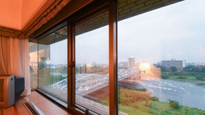A room with a large window overlooking a cityscape and a bridge. - Gunma Royal Hotel (Maebashi)