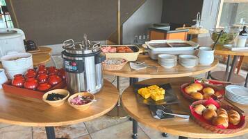A breakfast buffet with various food items and cooking equipment.