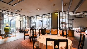 A dining area with round tables, chairs, and a decorative vase. - Gunma Royal Hotel (Maebashi)