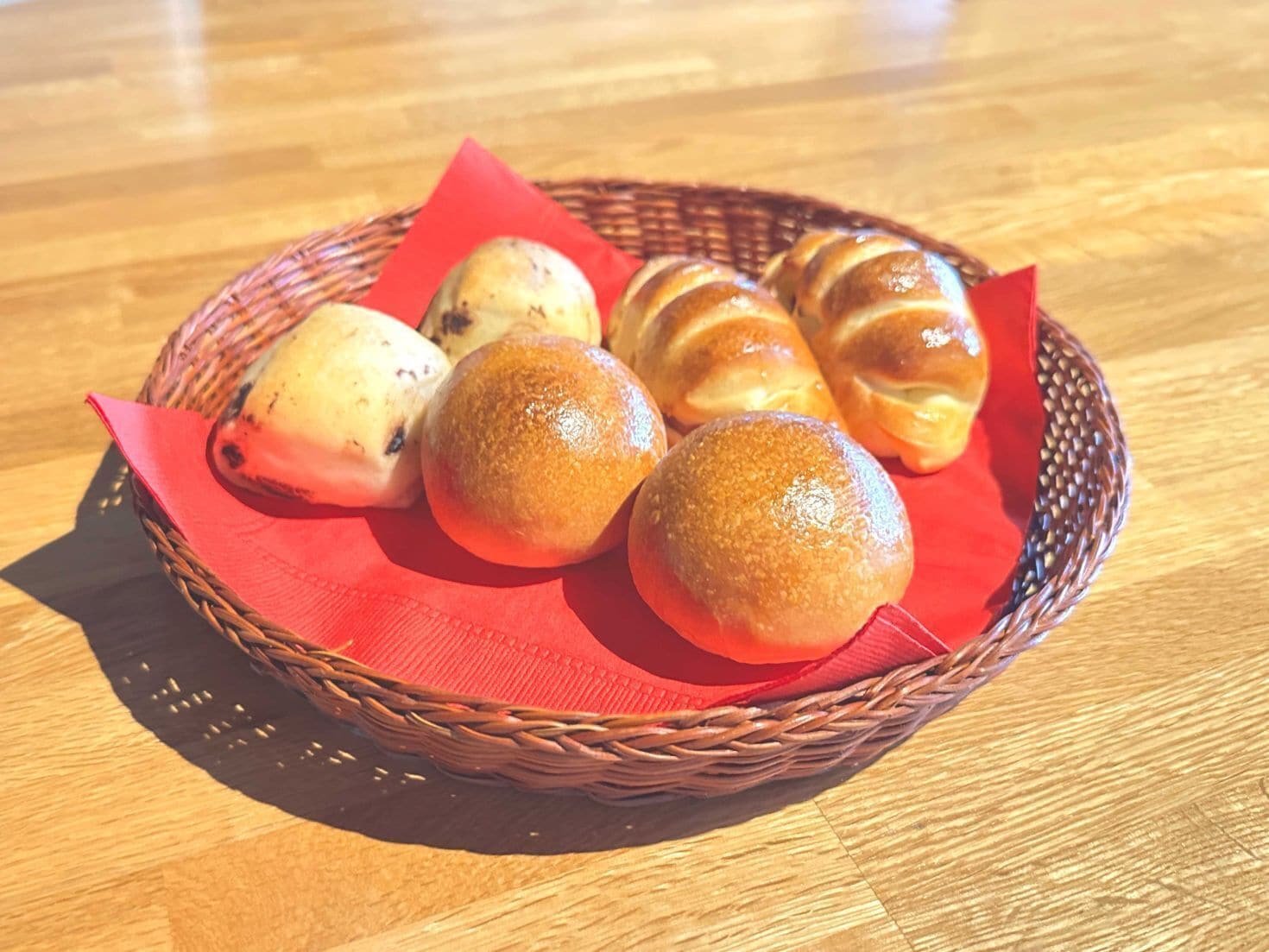 A basket containing various baked goods on a wooden table.