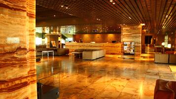A spacious lobby with a marble floor, modern furniture, and a patterned ceiling.