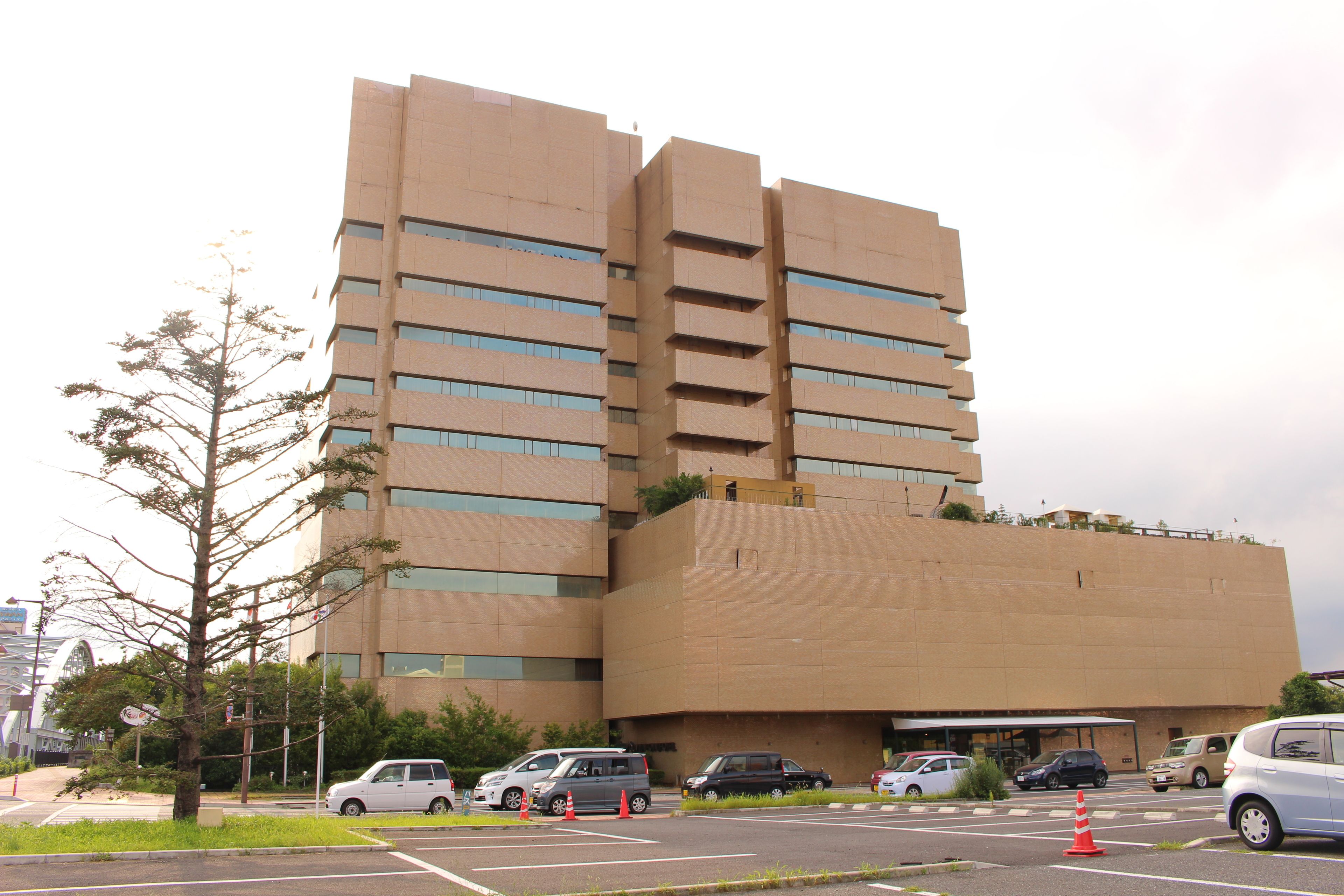 Un edificio de varios pisos con un diseño arquitectónico moderno, que presenta un techo plano y una serie de balcones.