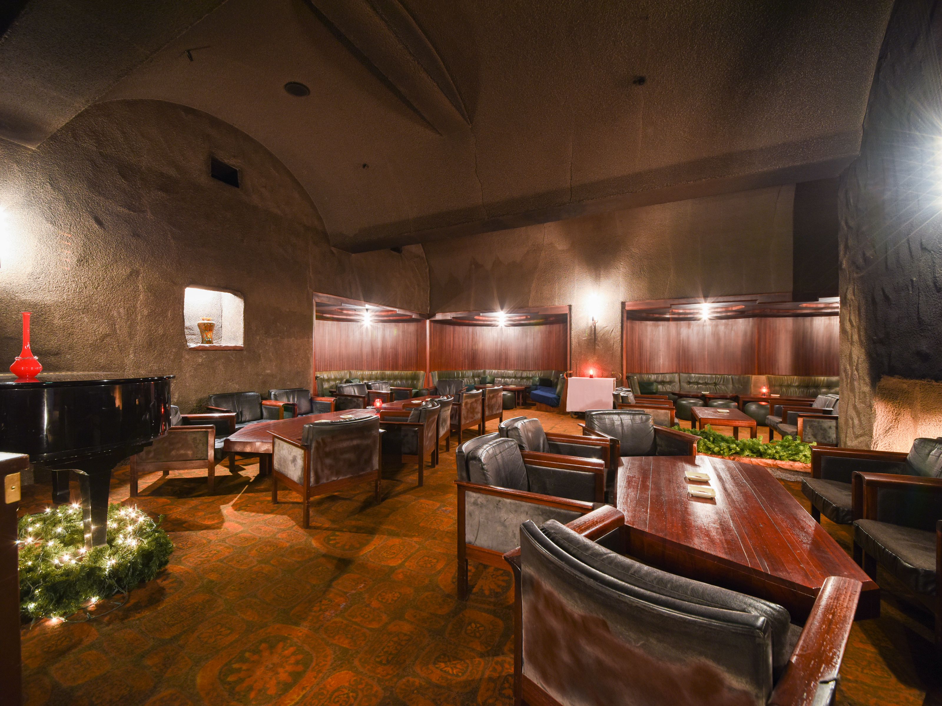 A spacious lounge area with multiple seating options, including sofas and tables, arranged in a semi-circular layout.
