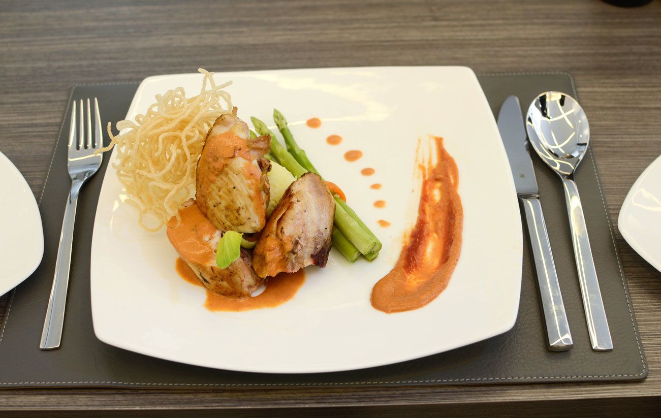 Un plato de comida con tenedor y cuchillo sobre un camino de mesa oscuro.
