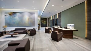 A modern hotel lobby with a large abstract painting, comfortable seating, a reception desk, and a minimalist design. - Space Apartments (Dhaka)