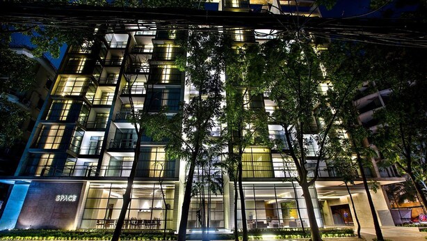 A modern building with multiple floors, large windows, and a well-lit entrance area. - Space Apartments (Dhaka)