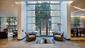 A spacious lobby with a large glass door, two sofas, a small table, and a lamp. - Space Apartments (Dhaka)