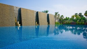 A clear blue infinity pool with a brick wall and palm trees in the background. - Queena Plaza Hotel Tainan (Tainan)