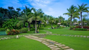 A lush garden with palm trees, a stone pathway, and a small pond. - Queena Plaza Hotel Tainan (Tainan)