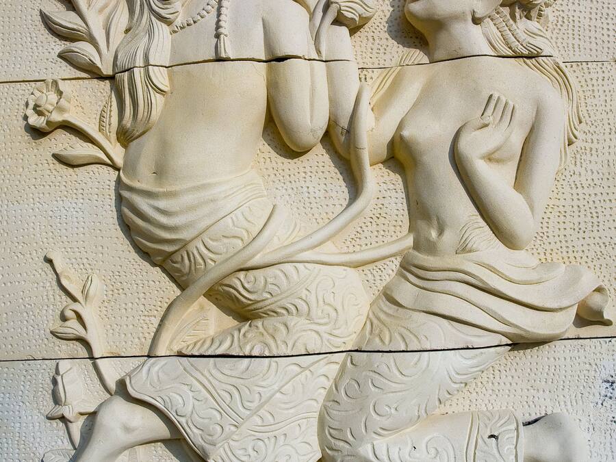 Een gedetailleerd stenen beeldhouwwerk van twee figuren verweven met bloem- en bladmotieven.