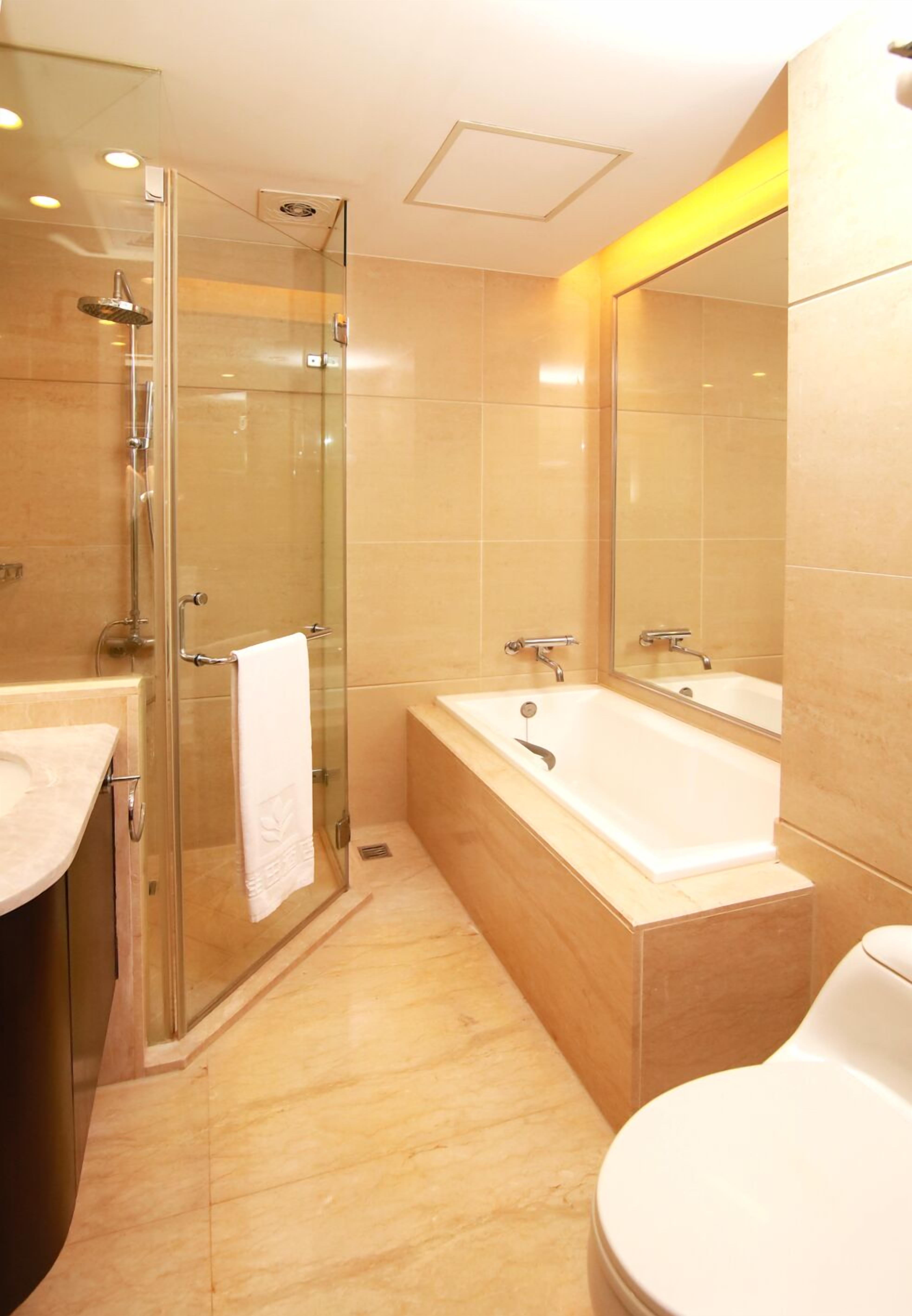 Un baño moderno con cabina de ducha de vidrio, bañera y retrete.