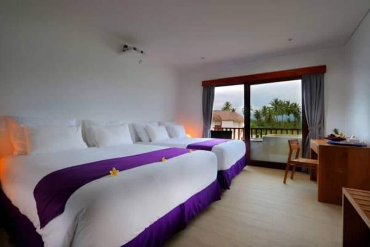 A hotel room with two beds, a balcony, and a desk.