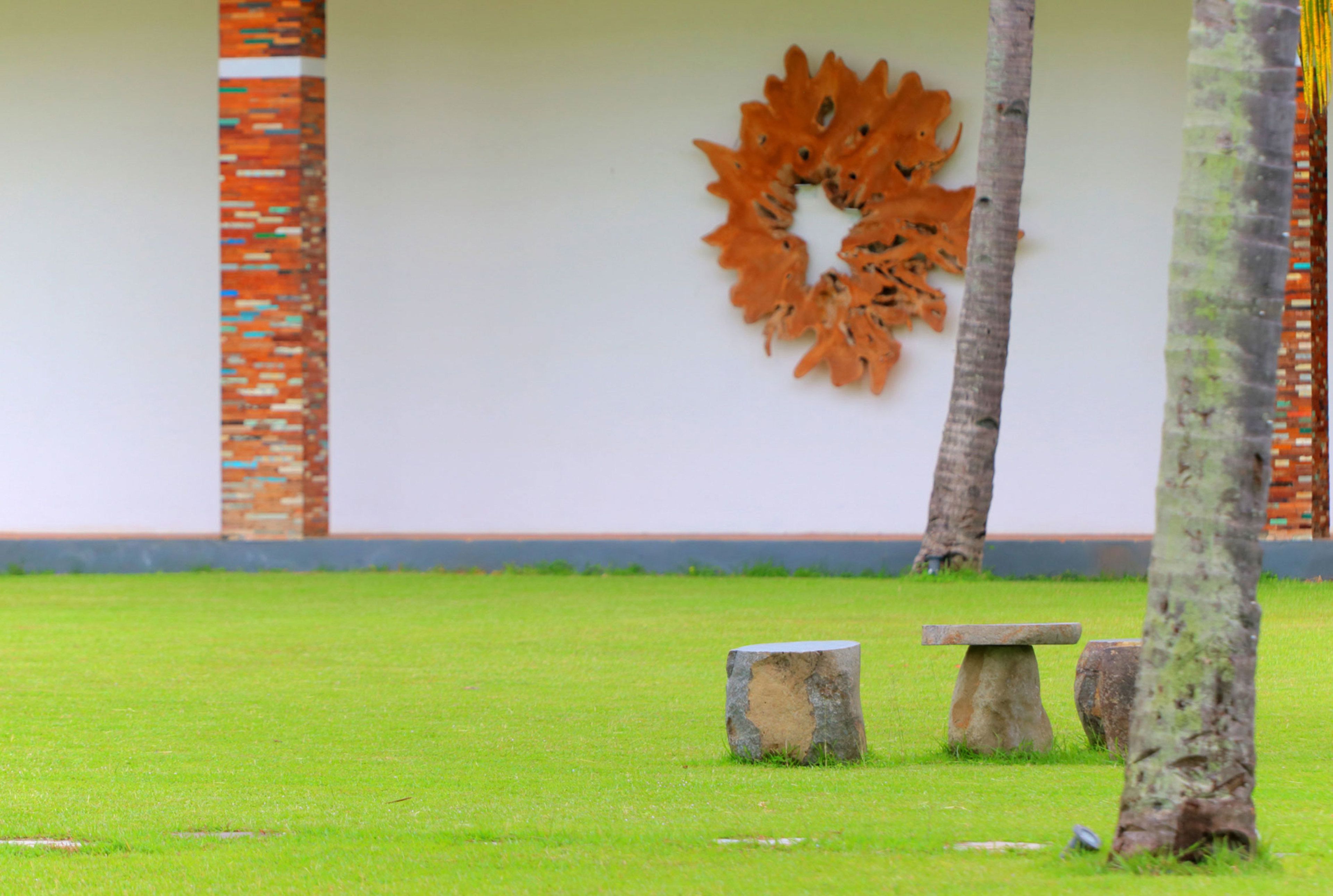 A grassy area with a stone bench and a decorative wall piece.