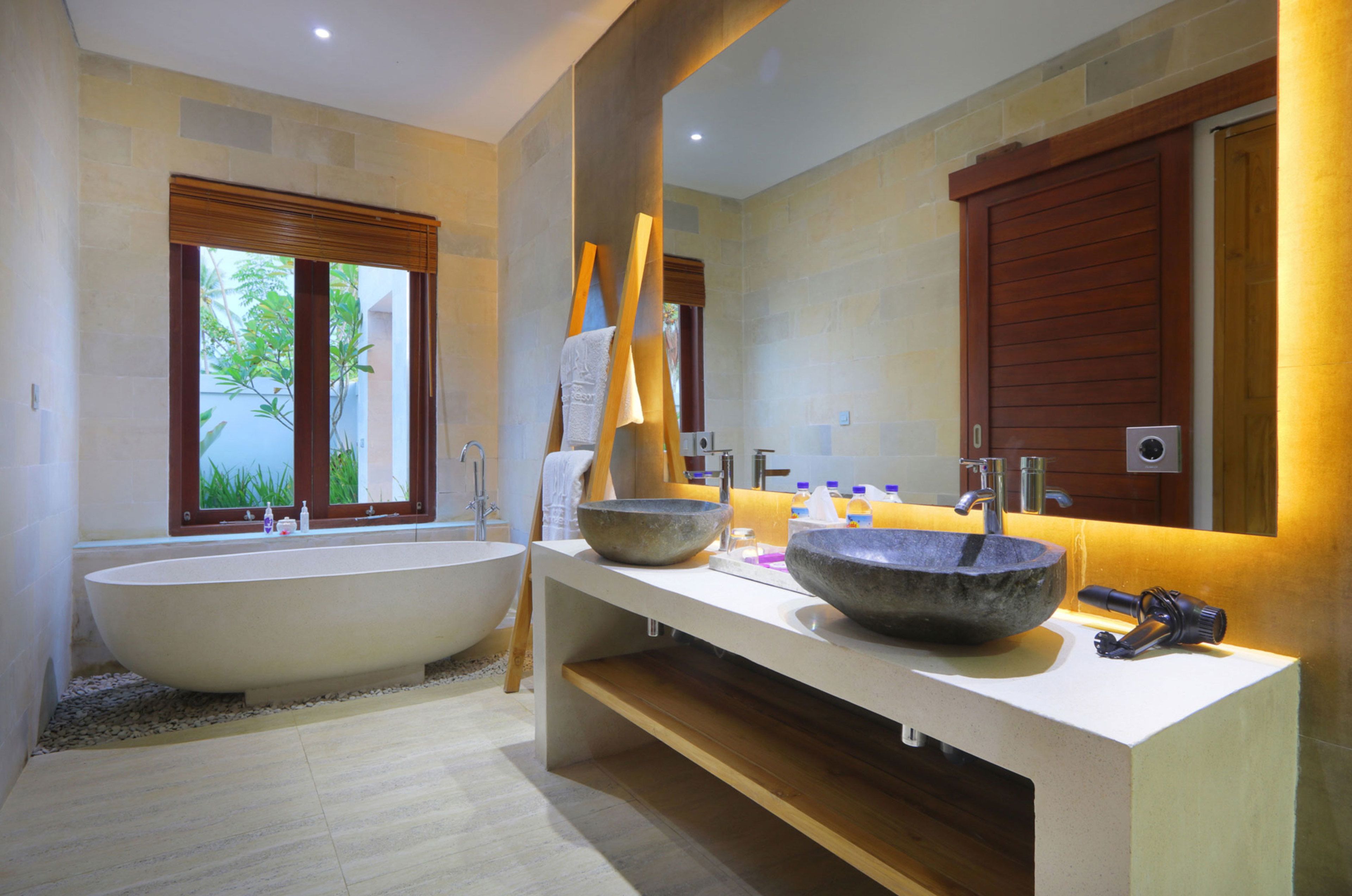 A modern bathroom with a large freestanding bathtub, a wooden ladder, and a large mirror.