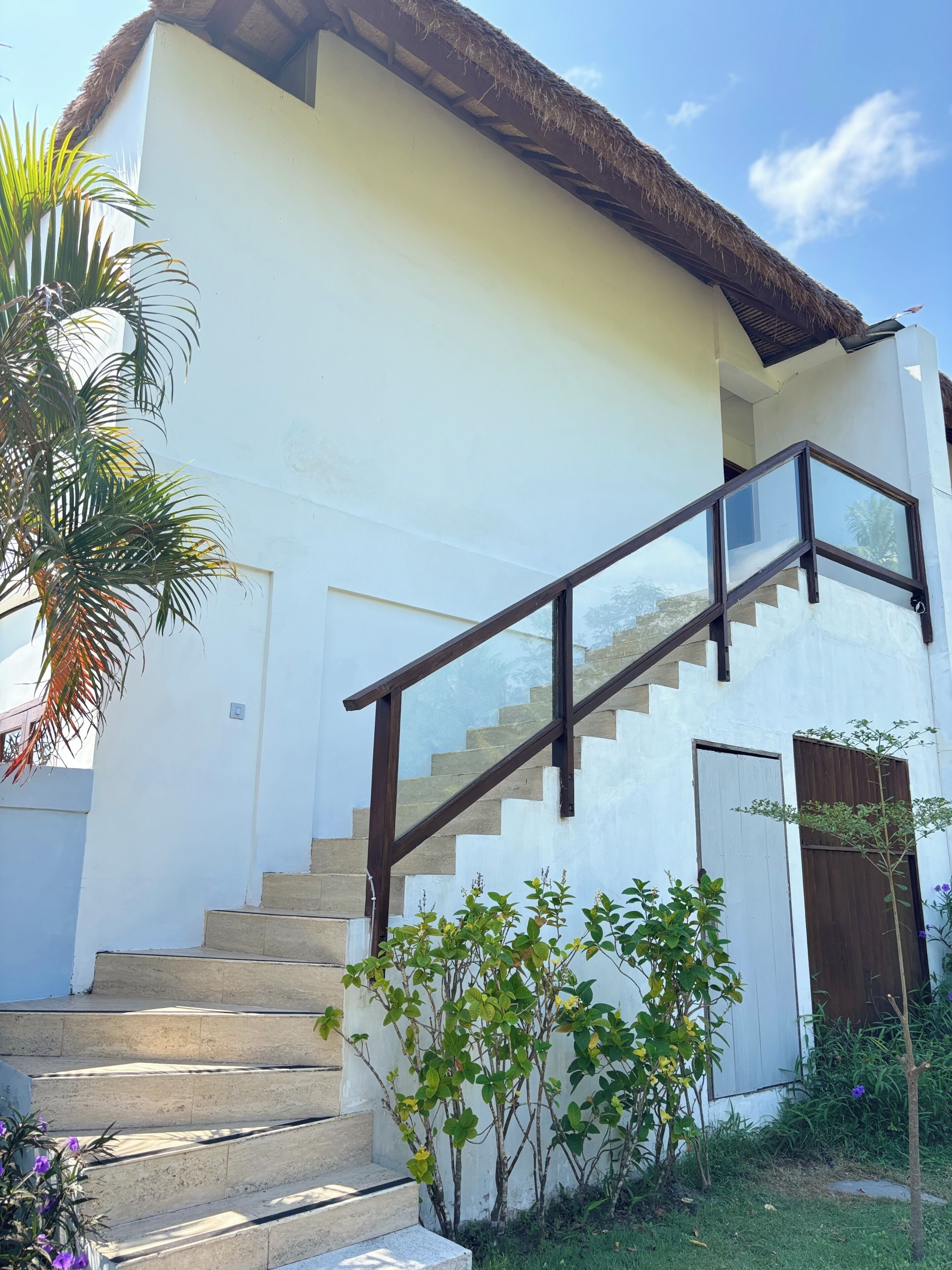 Un bâtiment blanc avec un escalier et un toit de chaume.