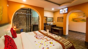 A hotel room with a large bed, a shower area, a desk, and a television. - Hotel Royal Safari (Sauraha)