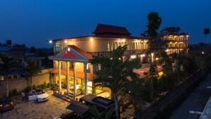 A hotel with a red roof, multiple balconies, and a well-lit entrance. - Hotel Royal Safari (Sauraha)