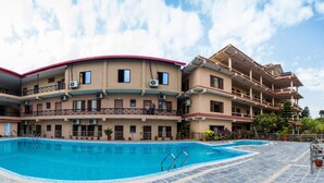 A multi-story hotel with a swimming pool, balconies, and potted plants. - Hotel Royal Safari (Sauraha)