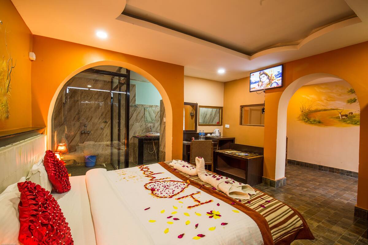 A hotel room with a large bed, a shower area, a desk, and a television.