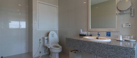 A modern bathroom with a toilet, sink, and large mirror.