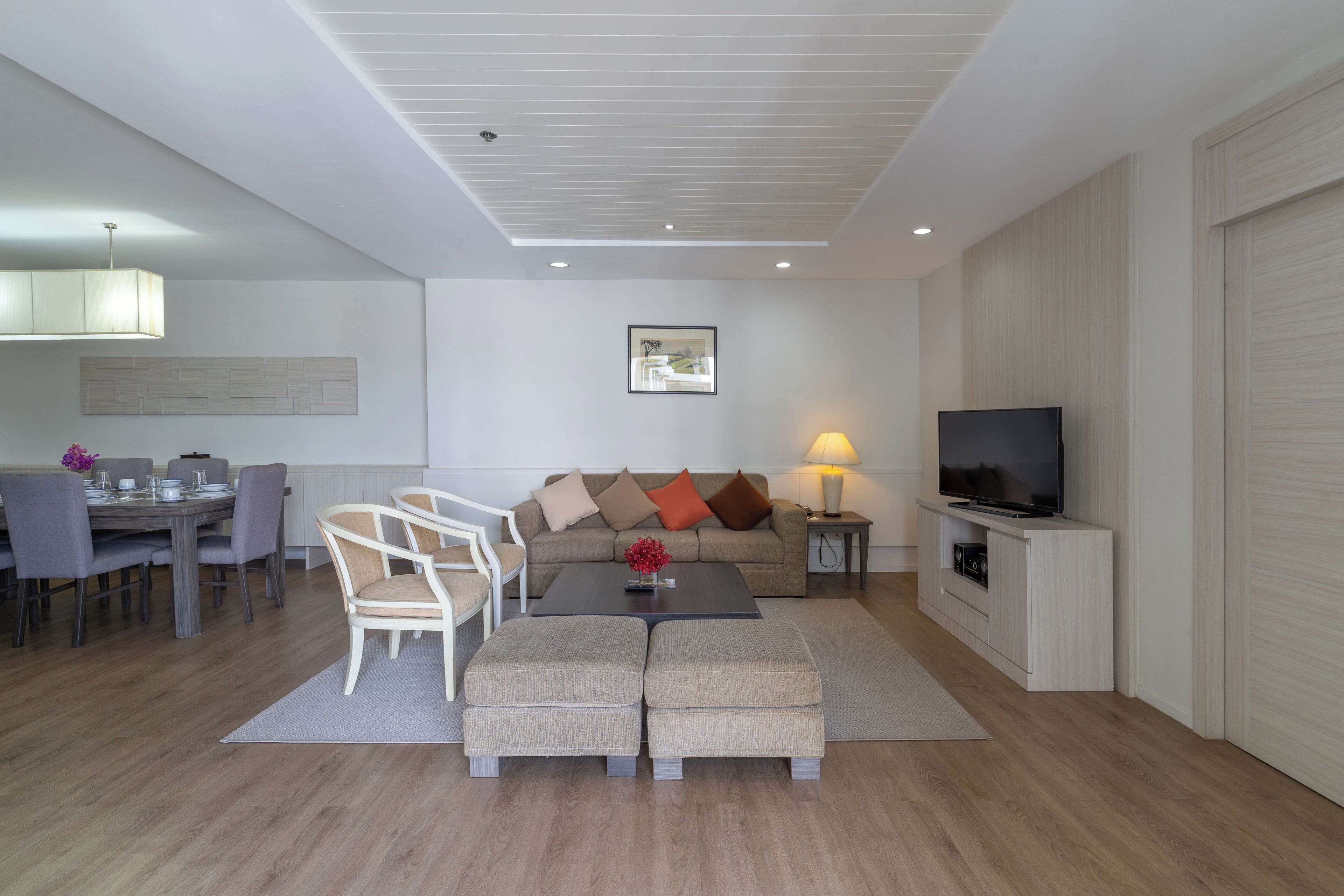 En moderne stue med spiseplads, en sofa, et sofabord, et fjernsyn og en lampe.