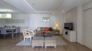 En moderne stue med spiseplads, en sofa, et sofabord, et fjernsyn og en lampe.
