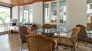 A dining area with wicker chairs, a glass table, and a view of the outdoors through large windows. - Kantary Bay Hotel And Serviced Apartments (Si Racha)