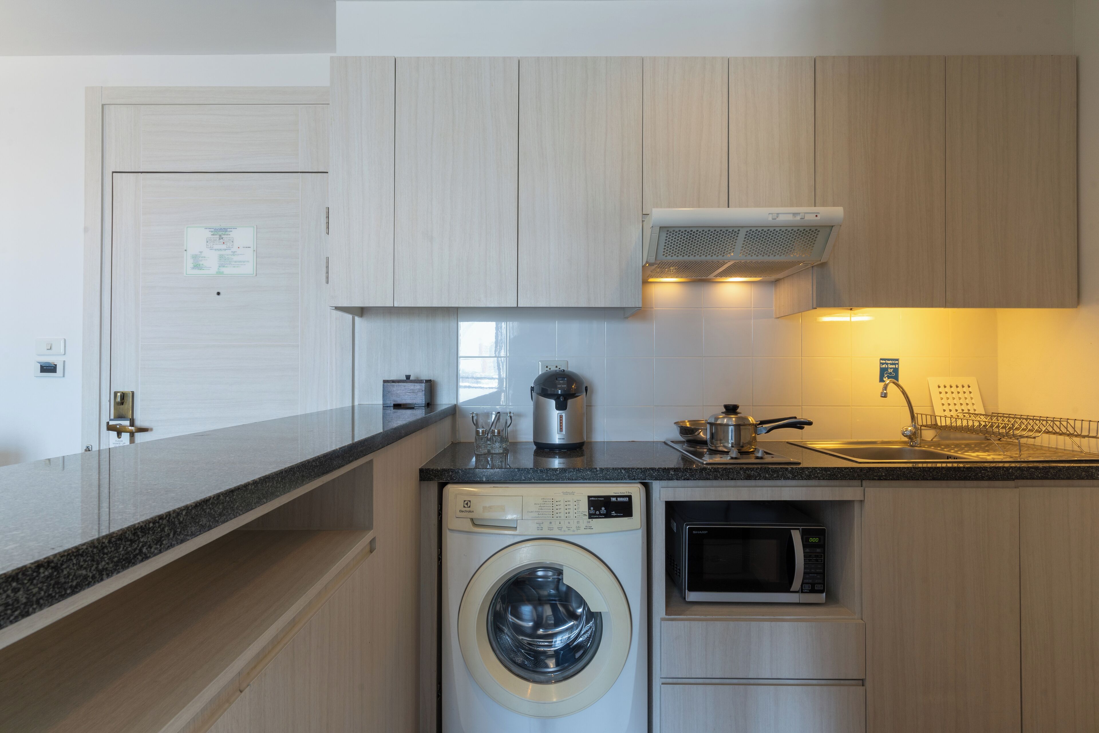 A compact kitchen with a washing machine, microwave, and a coffee maker.