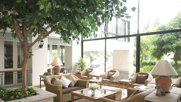 A spacious indoor seating area with wicker furniture, a coffee table, and a large window offering a view of greenery outside. - Kantary Bay Hotel And Serviced Apartments (Si Racha)
